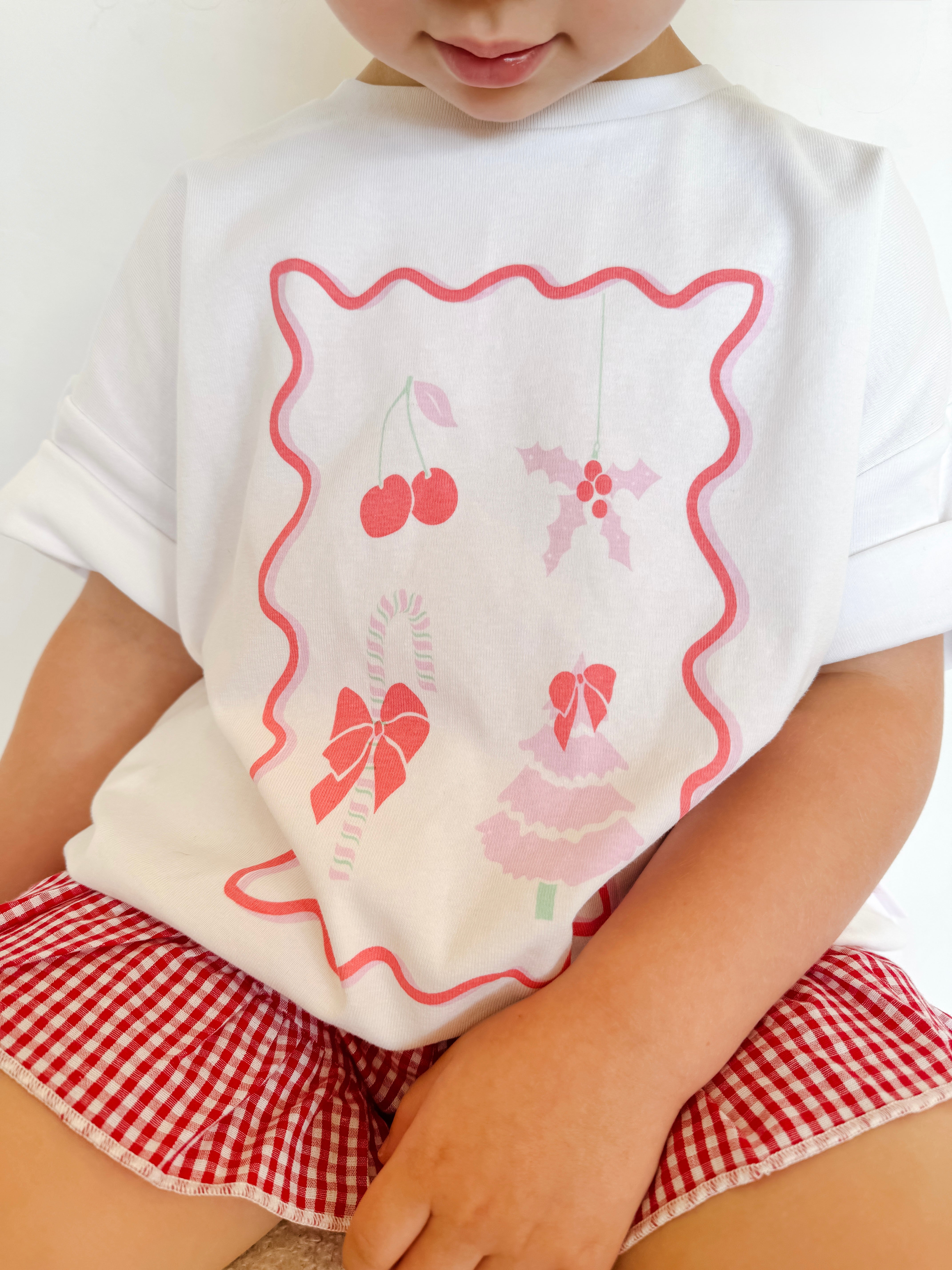 Rosie wearing Christmas stamp tee and cherry red gingham shorts