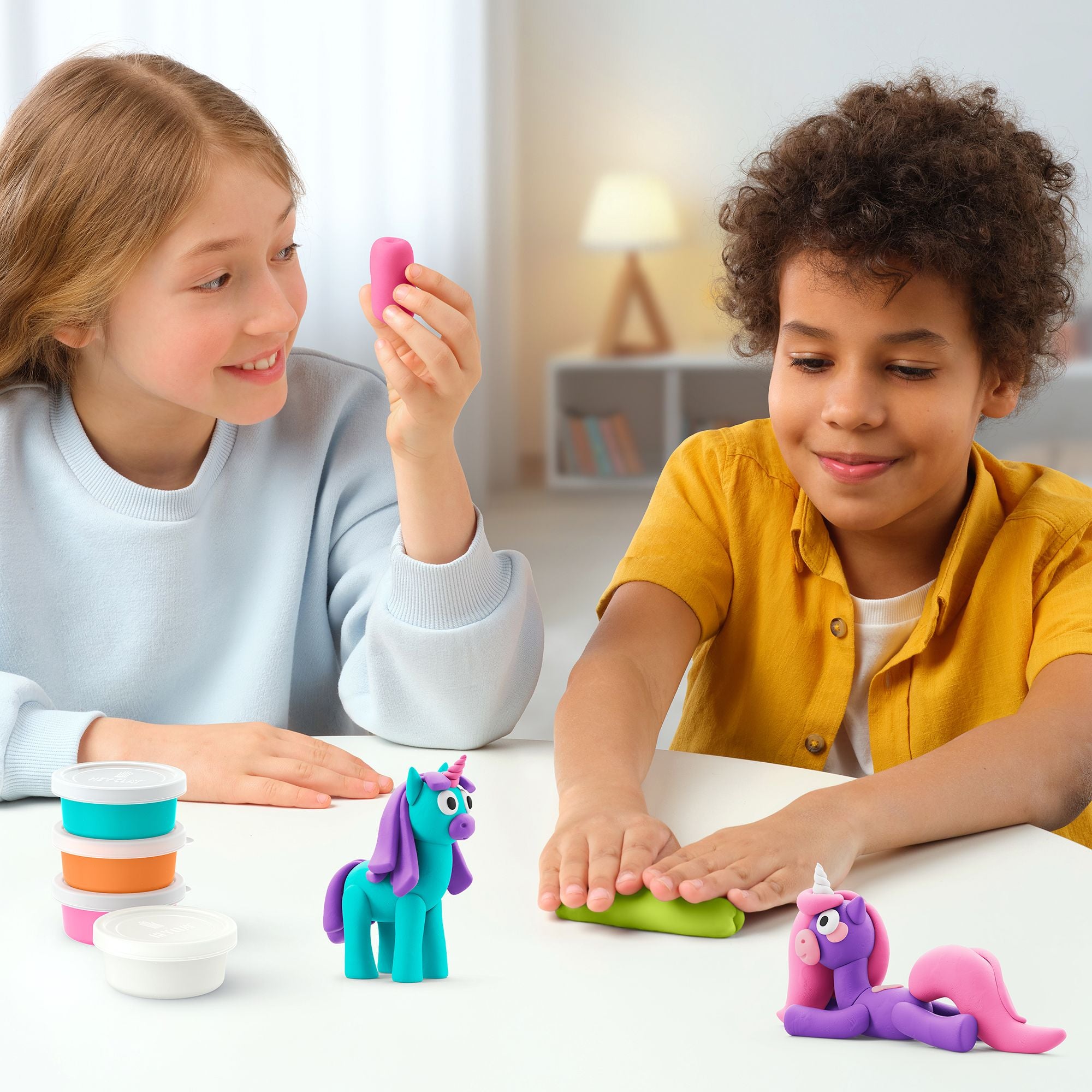 Two children playing with colorful hey clay unicorn set and toy unicorns on a table.