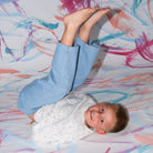 Child lying on a colorful abstract-patterned floor in grown funfetti pull over