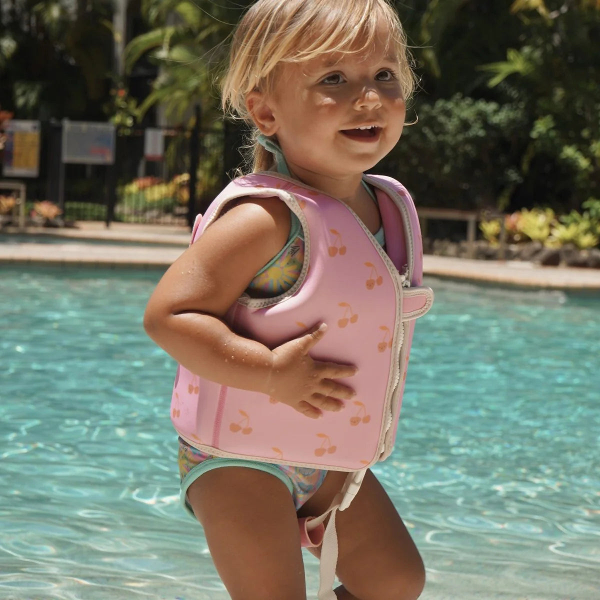 Child wearing Sunnylife Cotton Candy Cherry kids swim vest in the pool