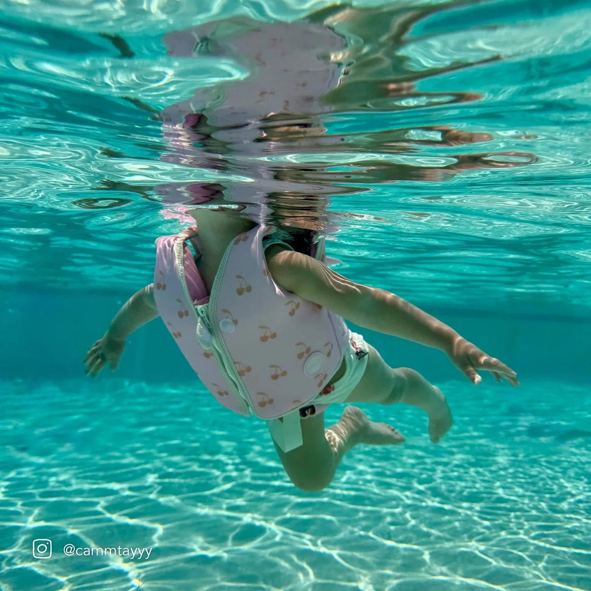 Child wearing Sunnylife Cotton Candy Cherry kids swim vest in the pool